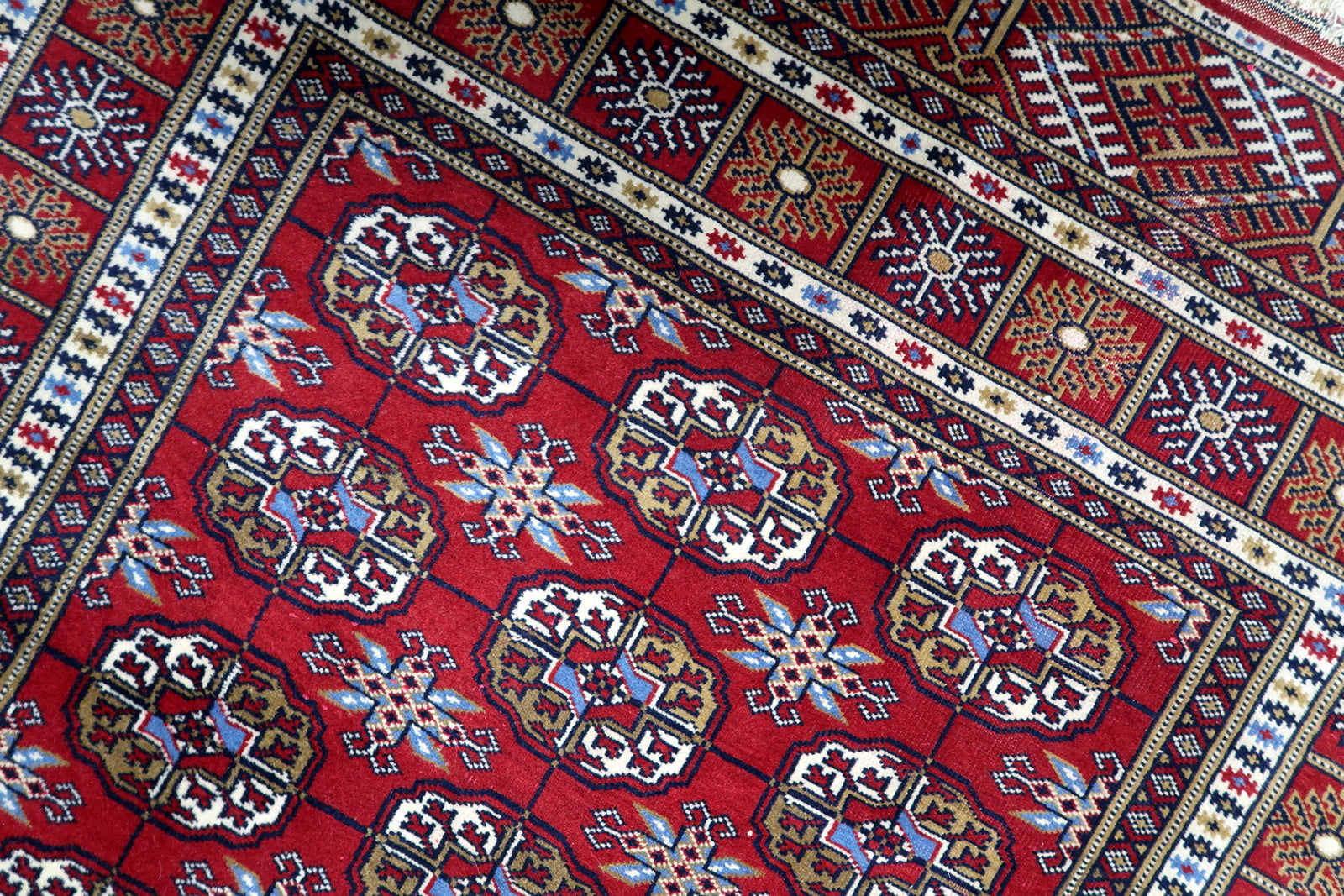 Hand-knotted wool rug in original good condition featuring dense symmetrical pattern and traditional tribal design