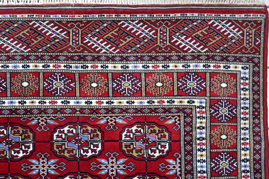 Close-up of intricate ivory, navy blue and copper-toned detailing inside traditional Bukhara guls on a Central Asian carpet