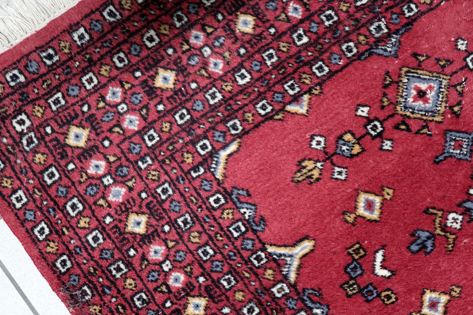 Full view of a vintage Central Asian rug featuring bold central panel framed by multiple intricate geometric borders