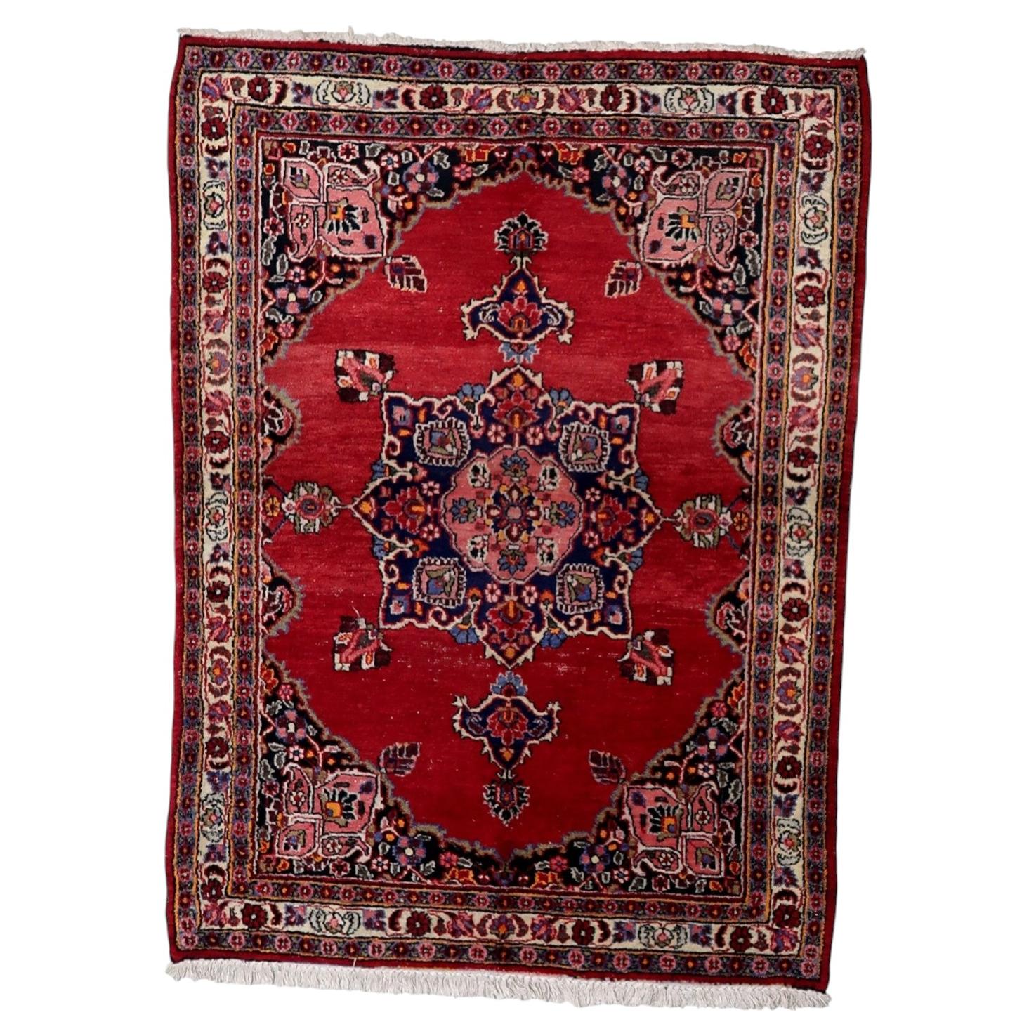Antique 1920s Persian Kazvin wool rug with warm red field and symmetrical central medallion in navy pink ivory and green, 4.4 x 5.9 feet