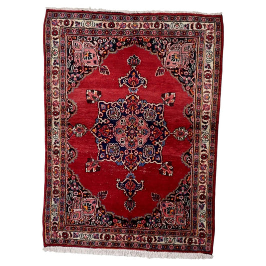 Antique 1920s Persian Kazvin wool rug with warm red field and symmetrical central medallion in navy pink ivory and green, 4.4 x 5.9 feet