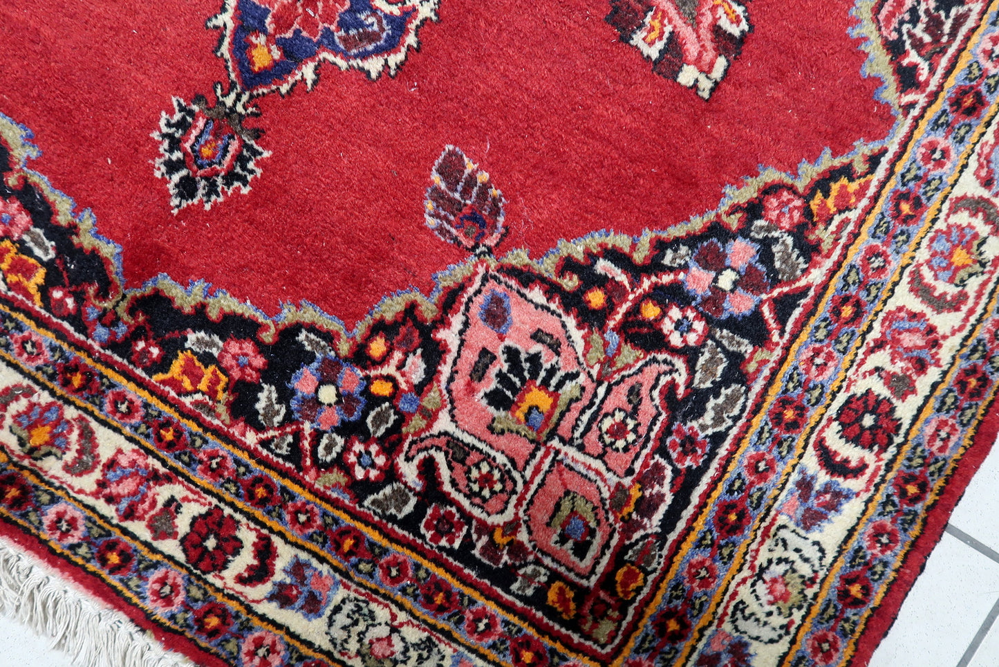 Hand-knotted wool rug in good antique condition featuring intricate botanical patterns and warm inviting palette