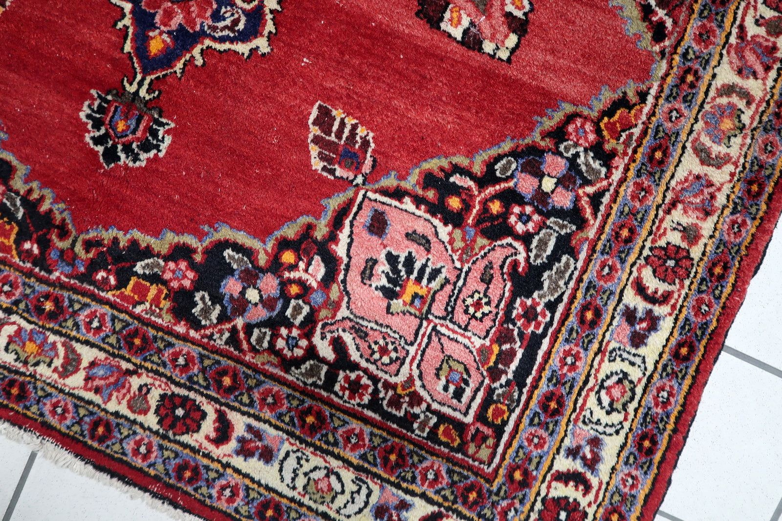 Full view of an antique Persian rug featuring balanced floral geometry and finely detailed multiple borders