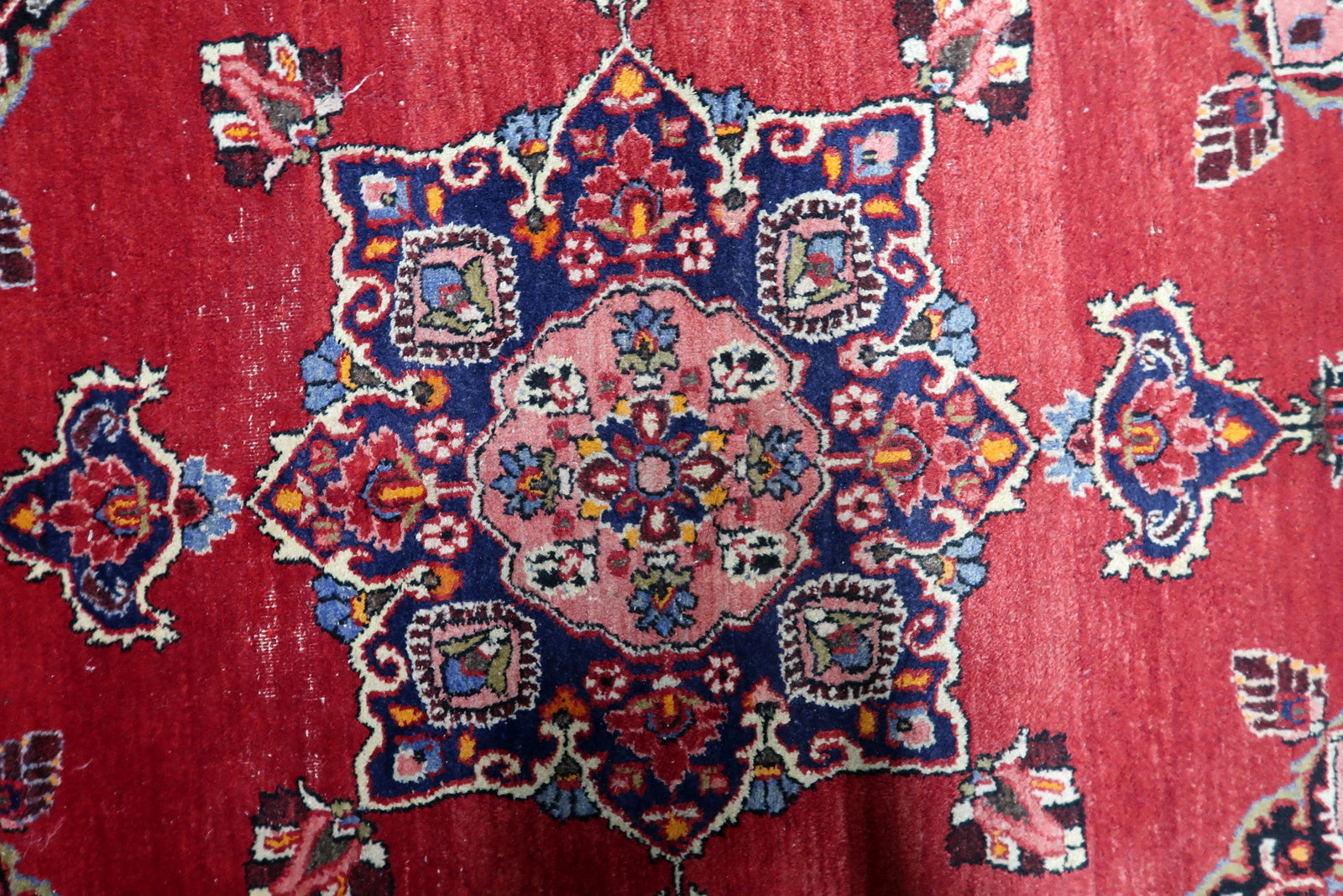 View of central medallion composition surrounded by finely detailed floral borders on an antique Persian floor covering
