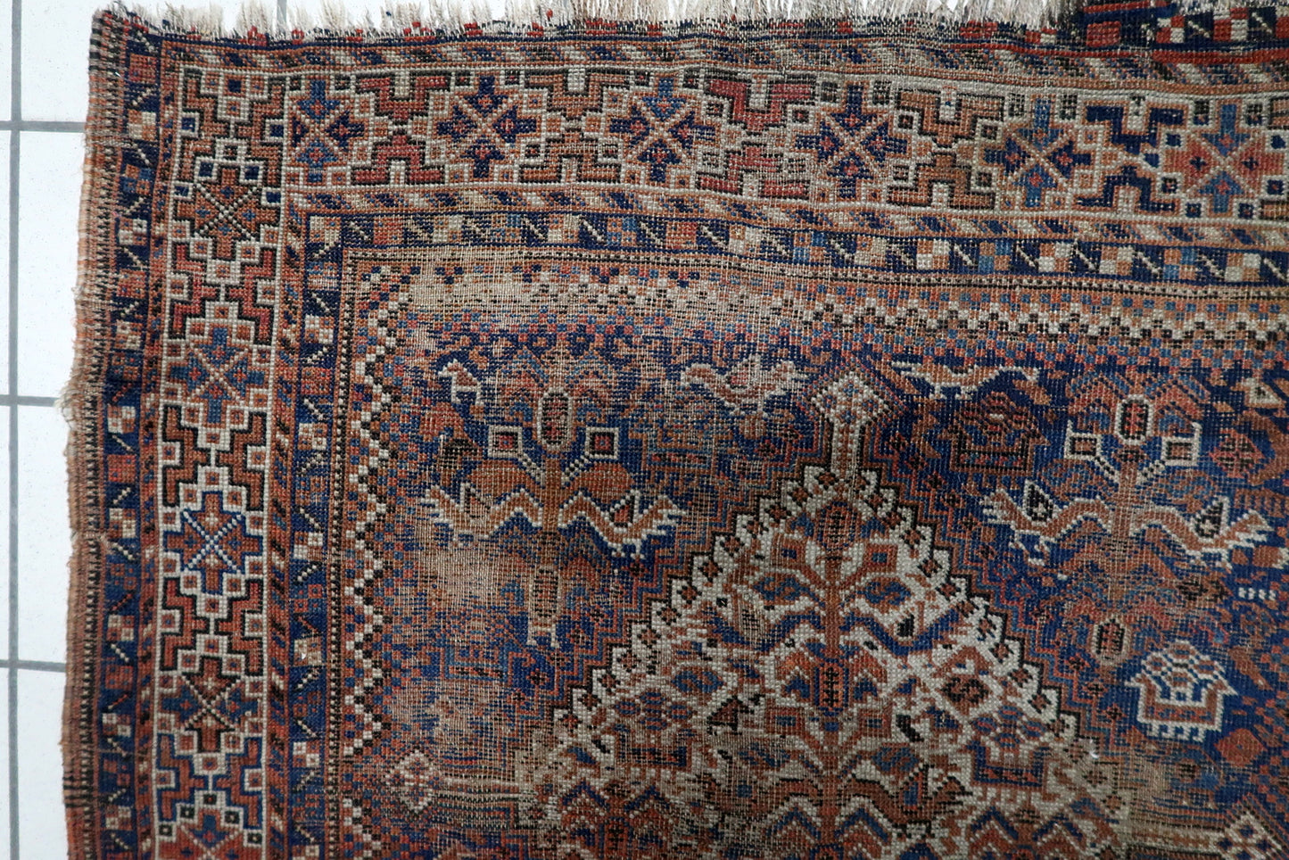Close-up of intricate small-scale tribal motifs and geometric patterns on a hand-knotted Persian Khamseh carpet