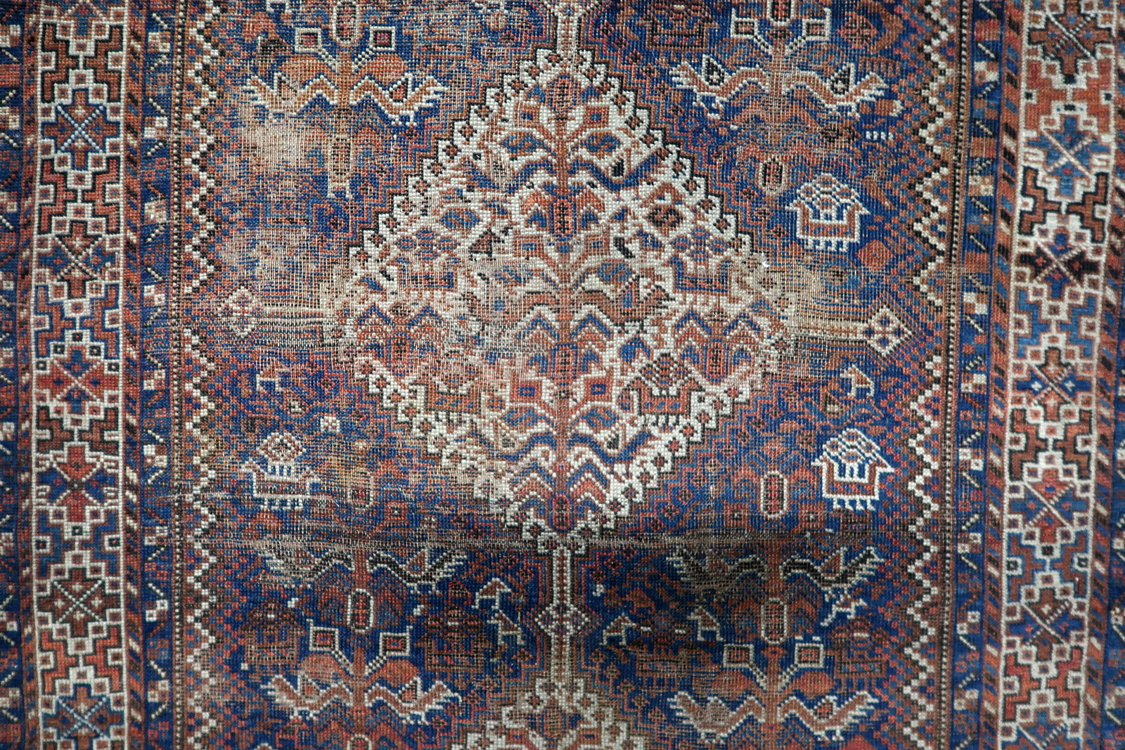 Detailed view of distressed condition showing areas of low pile, fading and frayed edges consistent with age