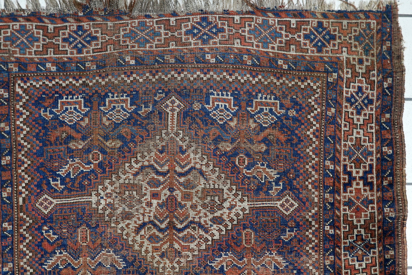 Hand-spun wool texture of an antique Persian Khamseh rug with time-earned imperfections and soulful character