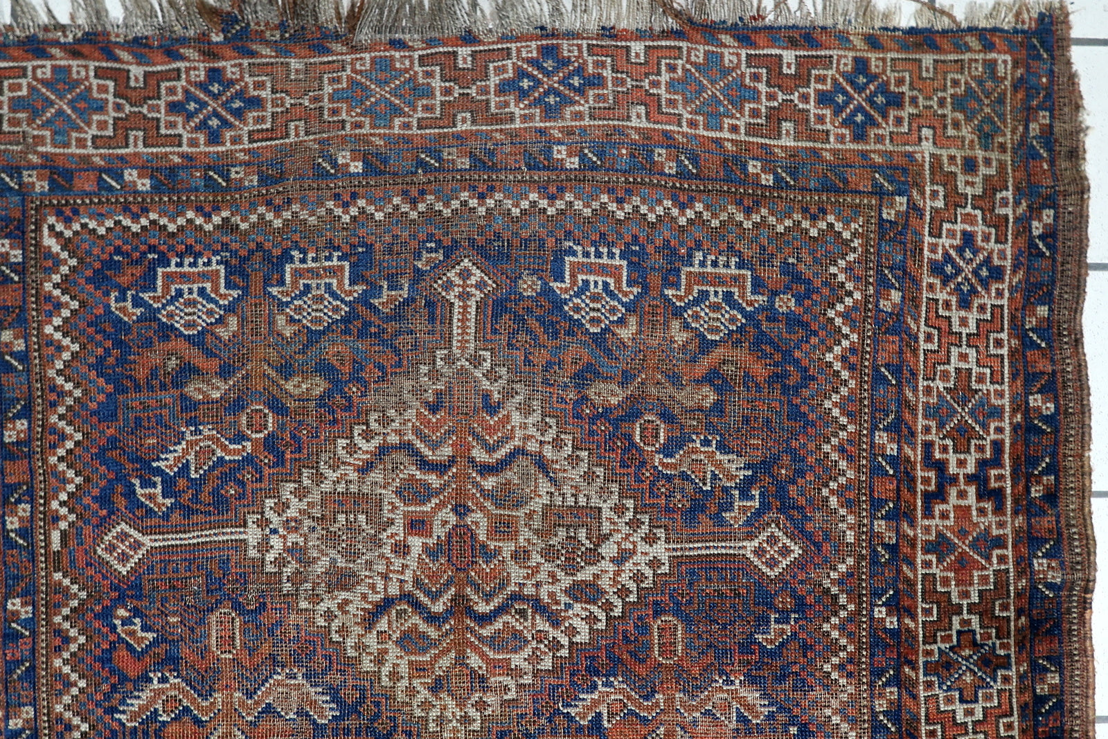 Hand-spun wool texture of an antique Persian Khamseh rug with time-earned imperfections and soulful character