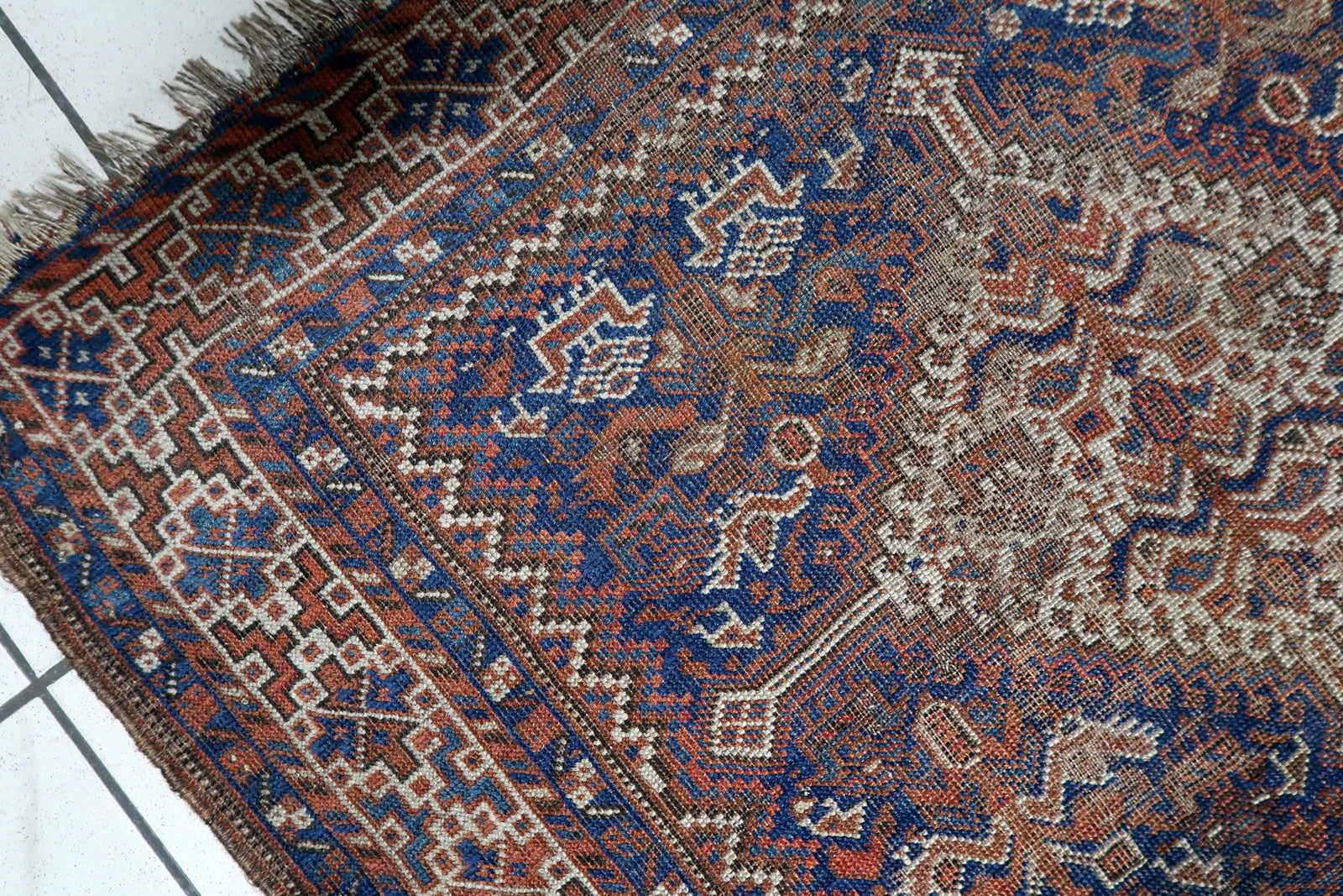 View of diamond medallion pattern surrounded by rhythmic geometric elements on a tribal Persian floor covering