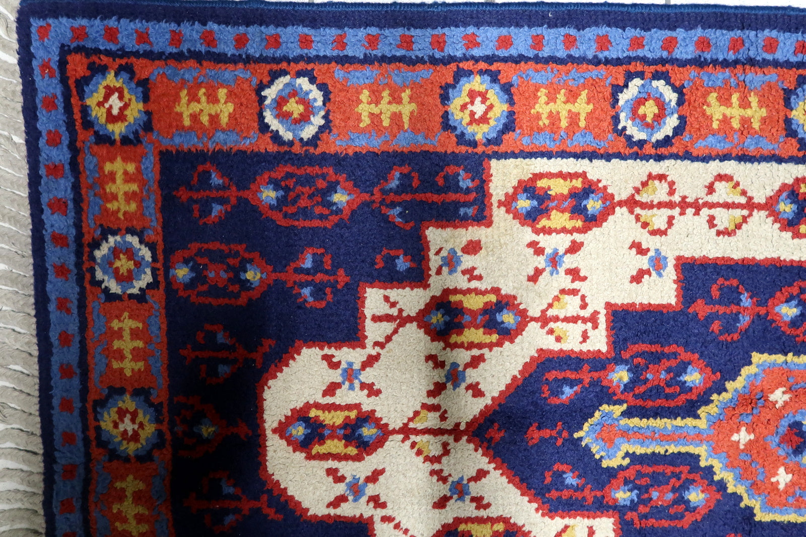 Warm red, blue, white and yellow vintage French rug with central geometric medallion and floral border motifs