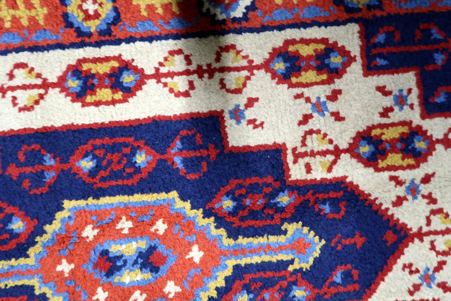 Close-up of symmetrical geometric and floral motifs surrounding the central medallion on a mid-century French carpet