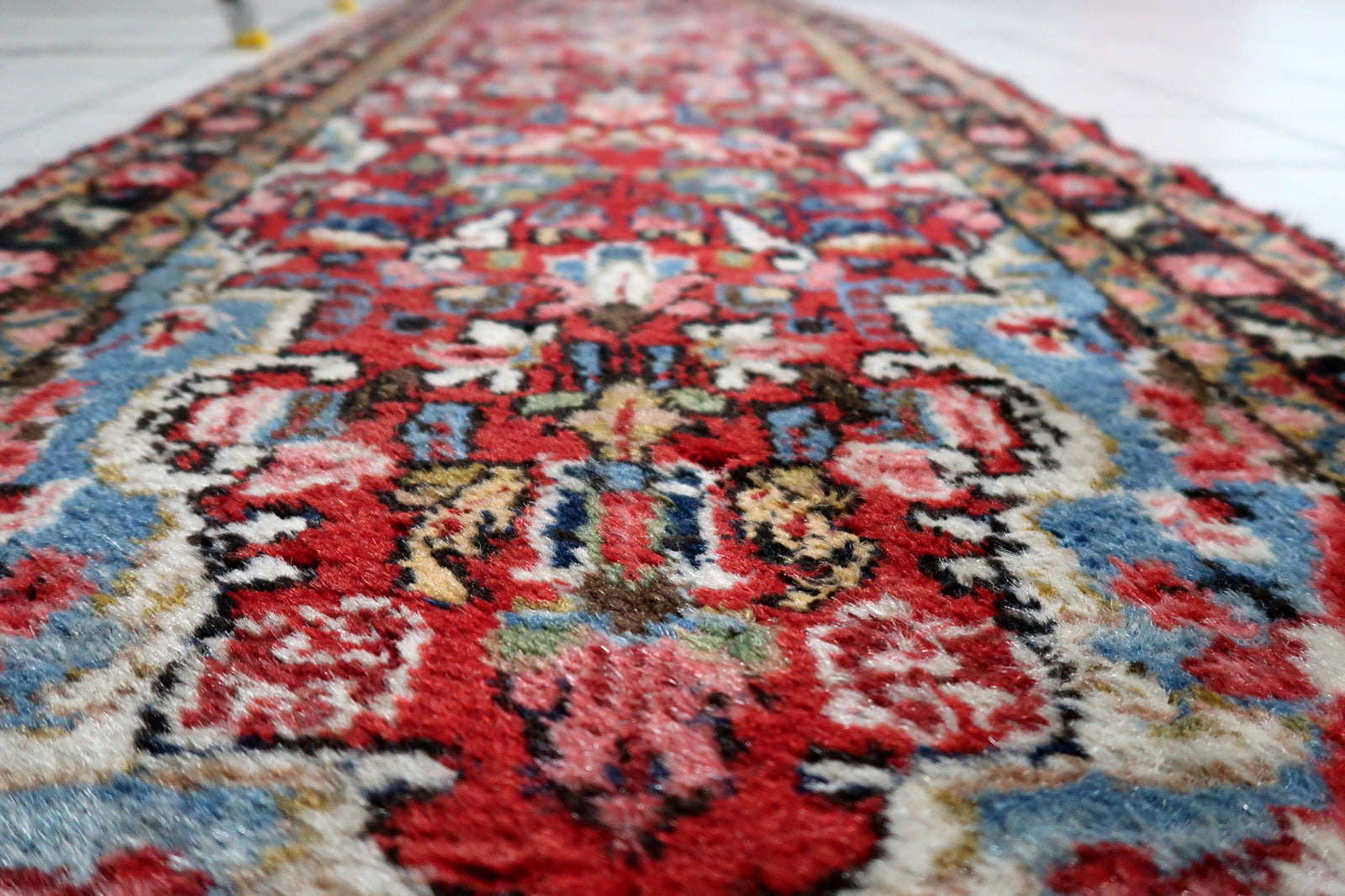 Wool pile texture of a distressed 1920s Persian rug with areas of low pile and gentle wear from age