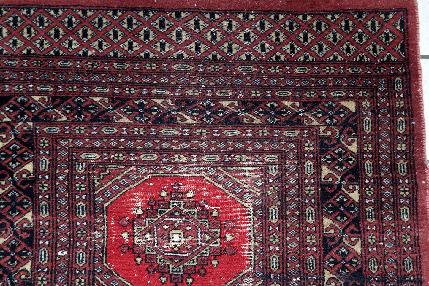 Close-up of a traditional Tekke-influenced gul motif with dark brown, black and ivory accents on a hand-knotted Bukhara carpet