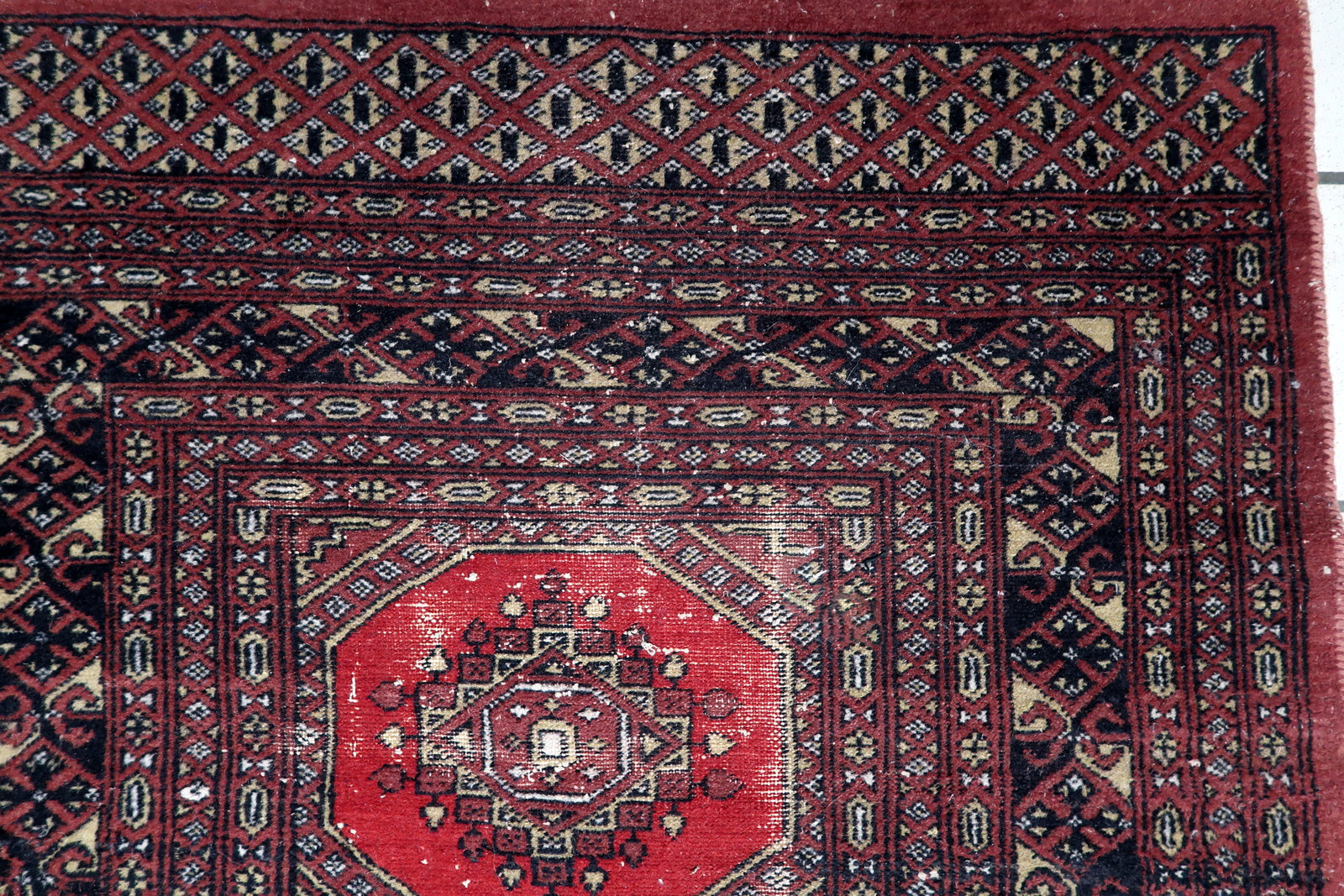 Close-up of a traditional Tekke-influenced gul motif with dark brown, black and ivory accents on a hand-knotted Bukhara carpet