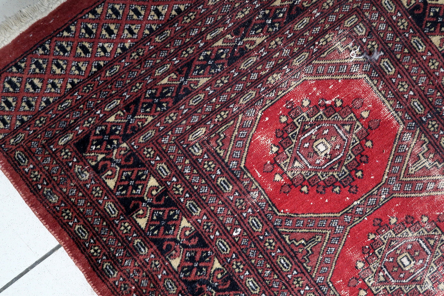 Full view of a Central Asian tribal rug featuring multiple geometric borders framing the central octagonal medallions