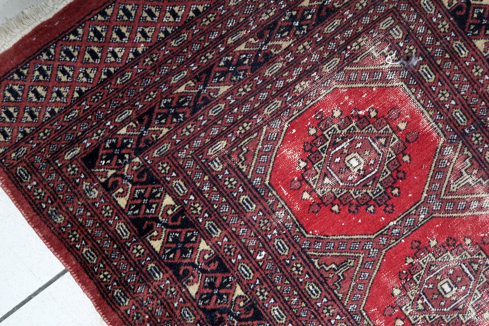 Full view of a Central Asian tribal rug featuring multiple geometric borders framing the central octagonal medallions