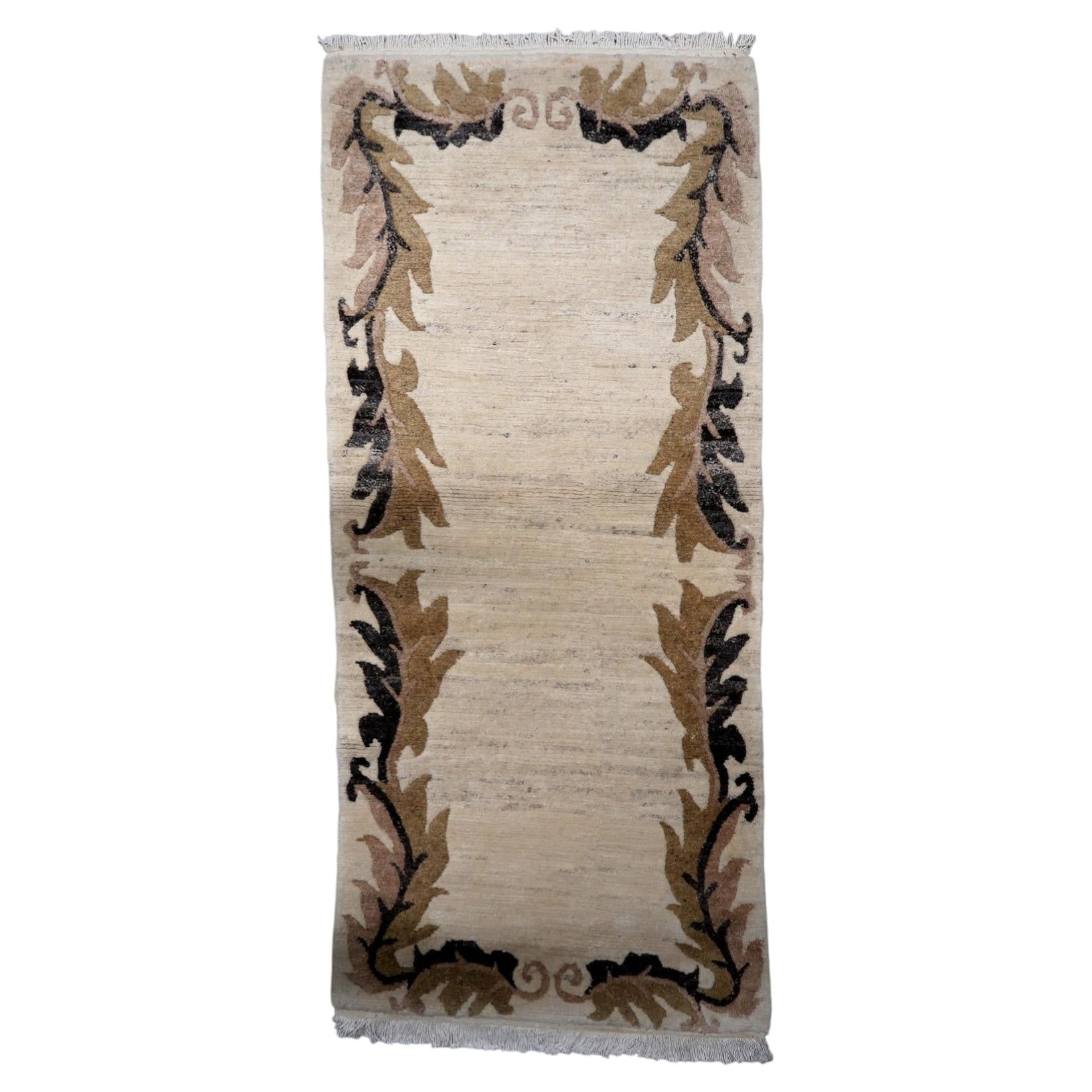 Vintage Tibetan Art Deco Khaden rug from the 1960s, 3 x 6.8 feet, in wool featuring a beige field with brown and charcoal stylized leaf border motifs.

