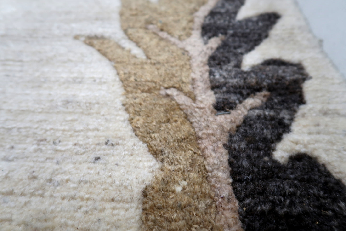 Close-up detail of the hand-knotted wool texture and the contrasting charcoal border pattern on a vintage Tibetan rug.

