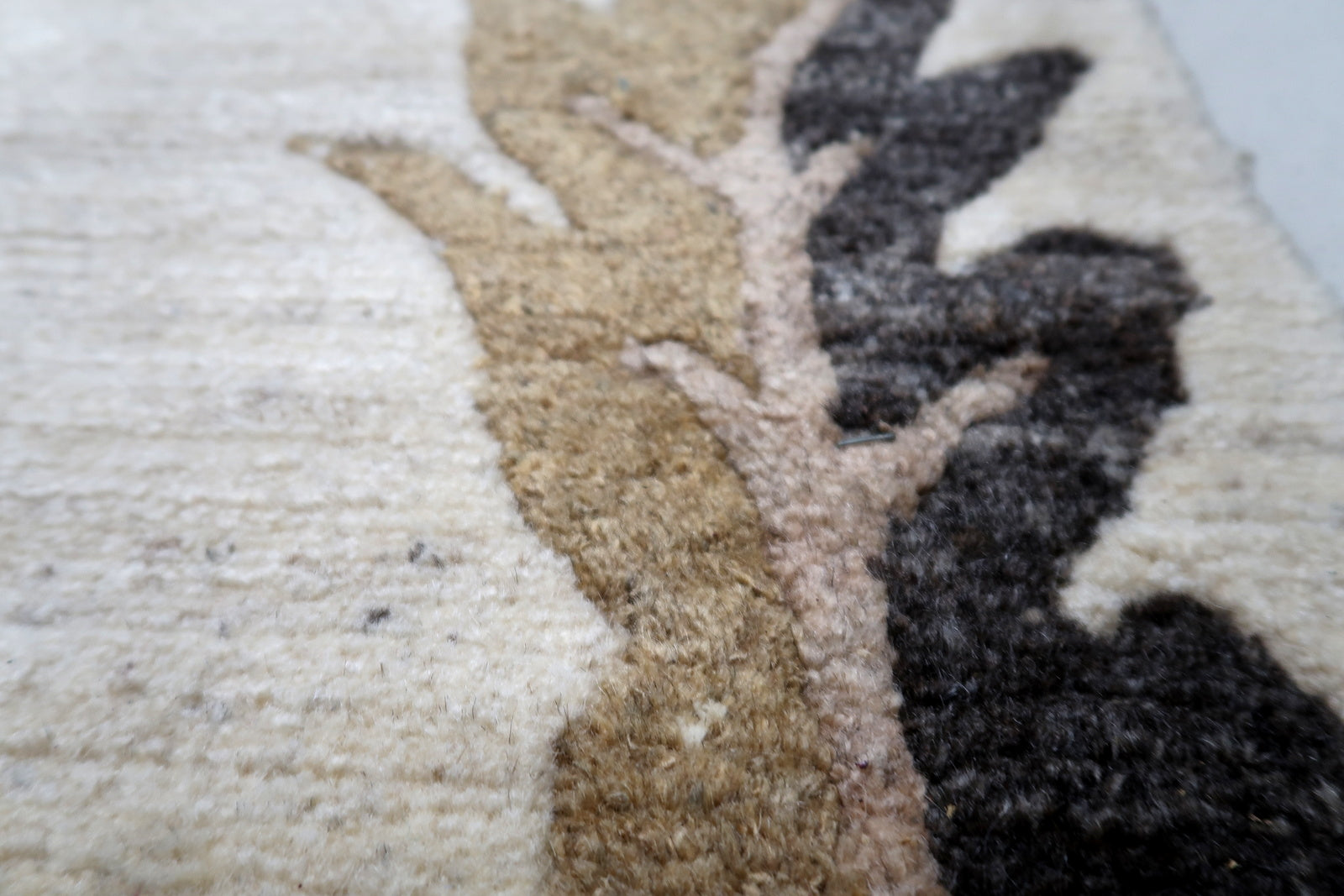 Close-up detail of the hand-knotted wool texture and the contrasting charcoal border pattern on a vintage Tibetan rug.

