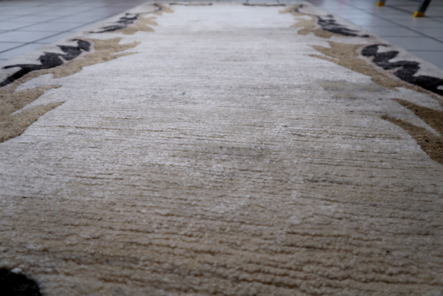 A 1960s Tibetan rug with soft, neutral colors, shown as an accent piece suitable for a reading corner or layered interior.

