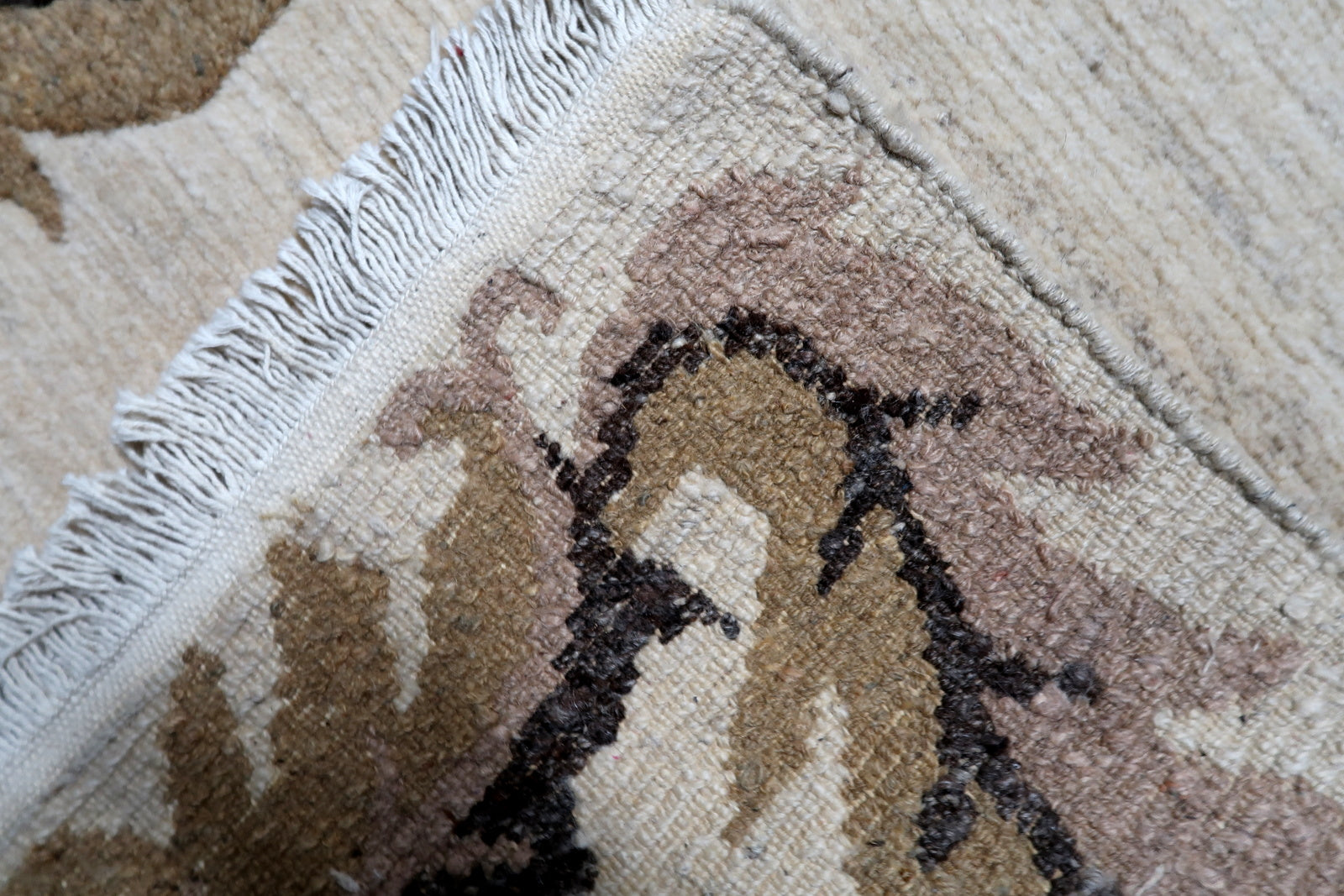 Close-up view of a hand-woven vintage Tibetan wool rug, showing the texture and gentle age-appropriate wear on the beige field.

