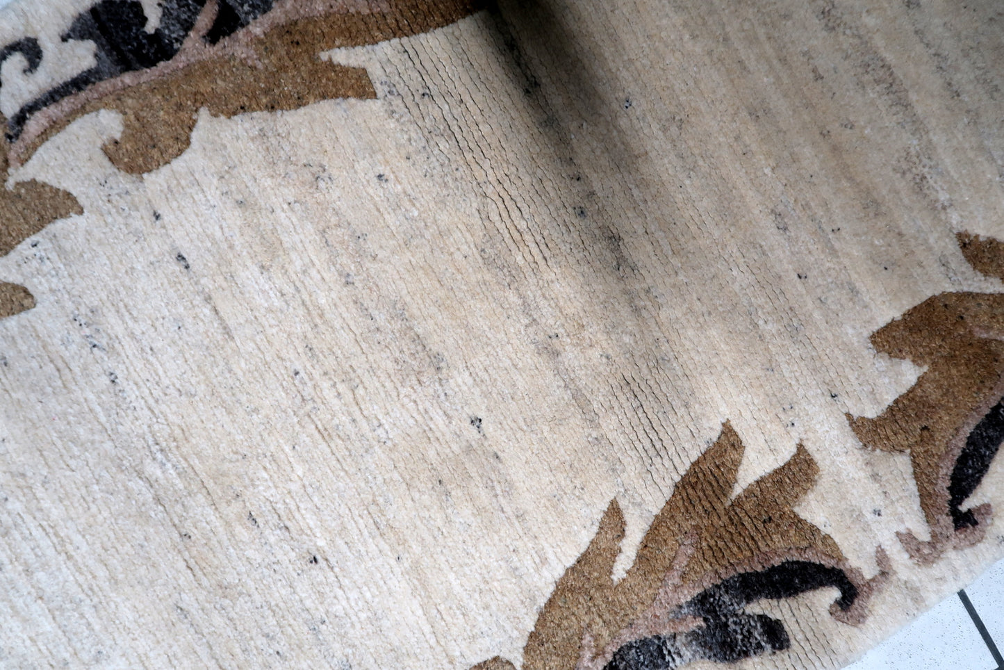 A handmade vintage Tibetan carpet, the Khaden rug displays mid-century minimalist design with a soft beige field and geometric border accents.

