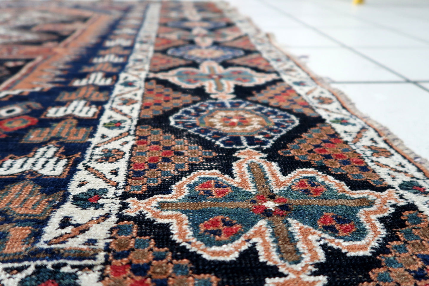 Vintage Persian rug featuring a striking all-over pattern with diamond medallions and geometric florals in classic tribal colors of red, navy, and rust.

