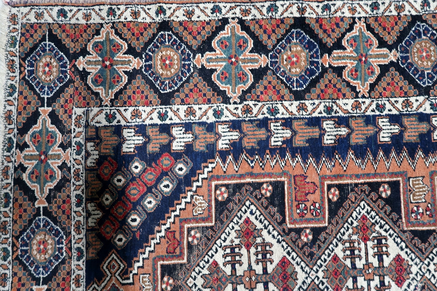 Geometric and floral tribal motifs in navy, rust, red, and green create multiple ornate borders on this 1920s Persian Afshar rug.

