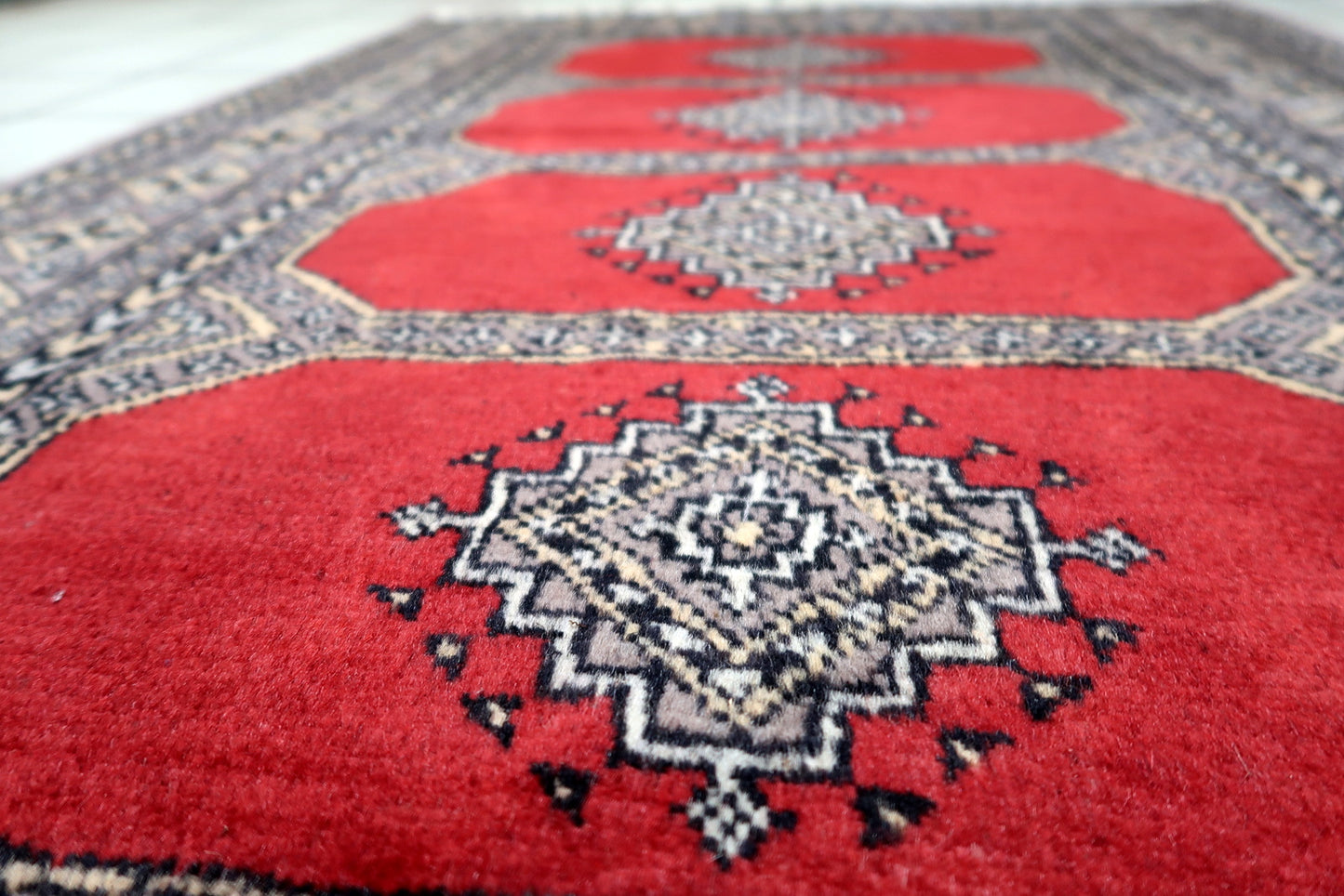 Example of mid-century Central Asian weaving: a Bukhara rug with symmetrical guls and multiple repeating borders in classic colors.

