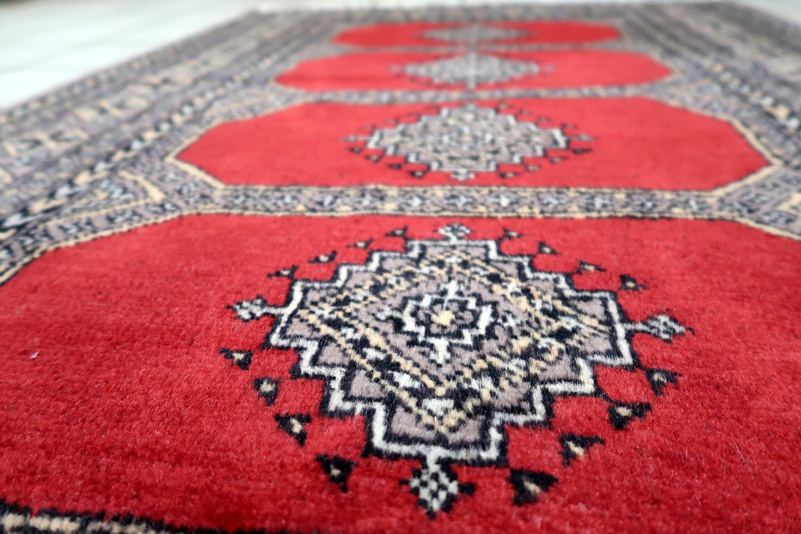Example of mid-century Central Asian weaving: a Bukhara rug with symmetrical guls and multiple repeating borders in classic colors.

