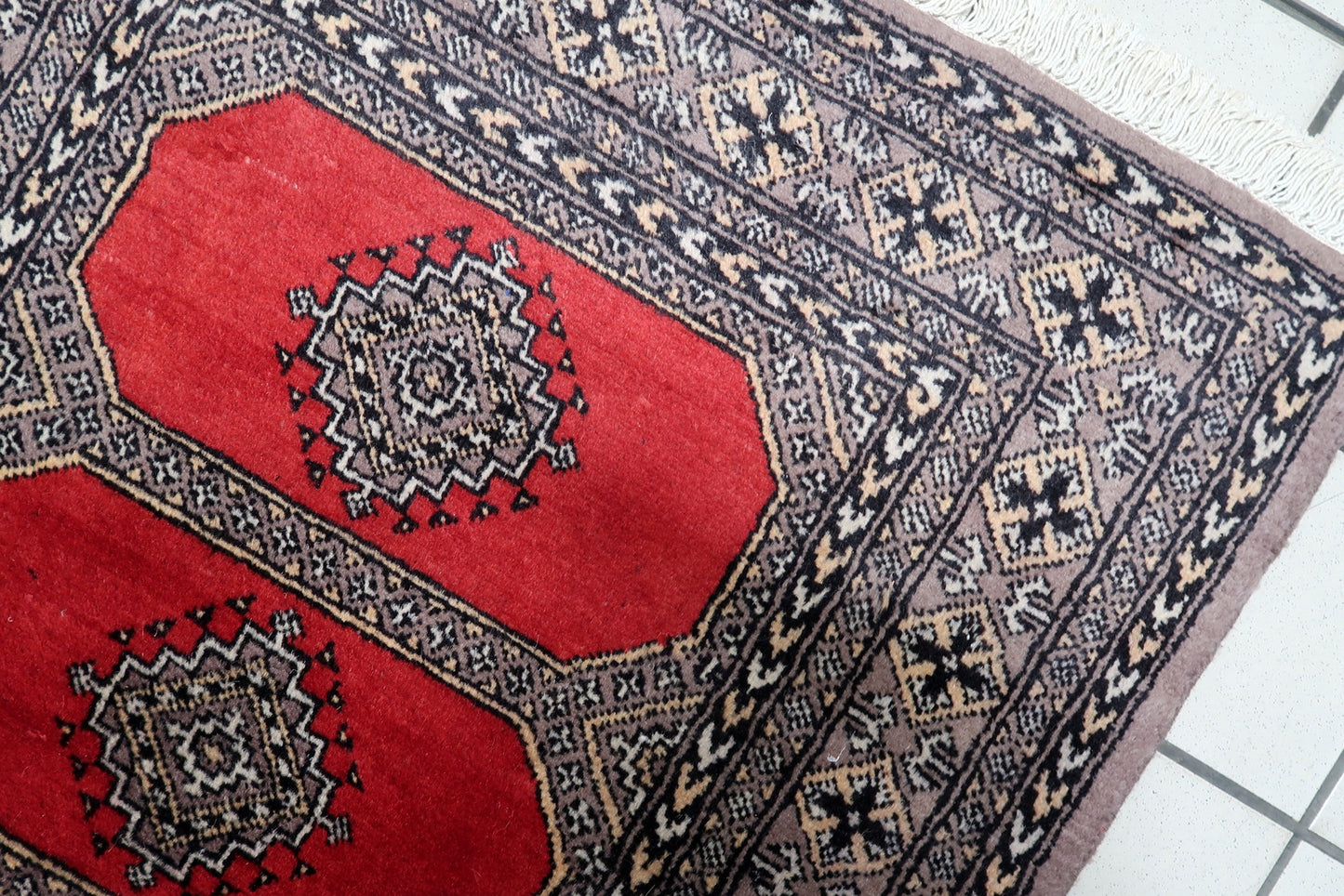 Full view of a vintage Central Asian rug showing four symmetrical octagonal guls arranged along a vibrant red field.

