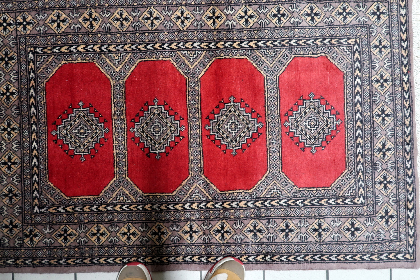 A 100% wool vintage Bukhara accent rug, hand-knotted in the 1960s, featuring classic tribal patterns in warm earth tones.

