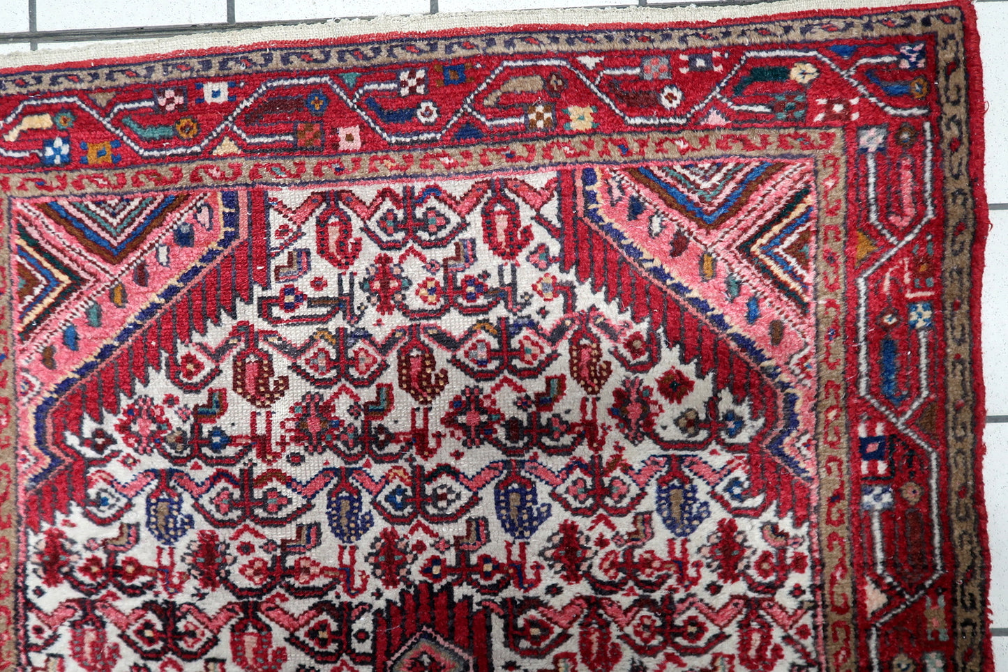 Close-up of antique Persian Hamadan rug displaying intricate geometric and floral border motifs

