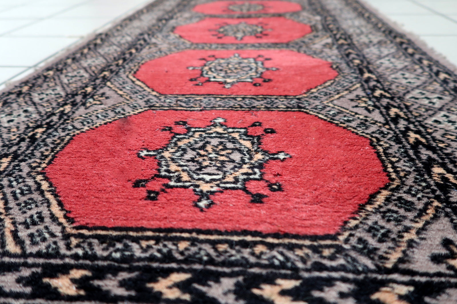 Close-up of geometric borders in black and ivory framing the red field of Bukhara runner
