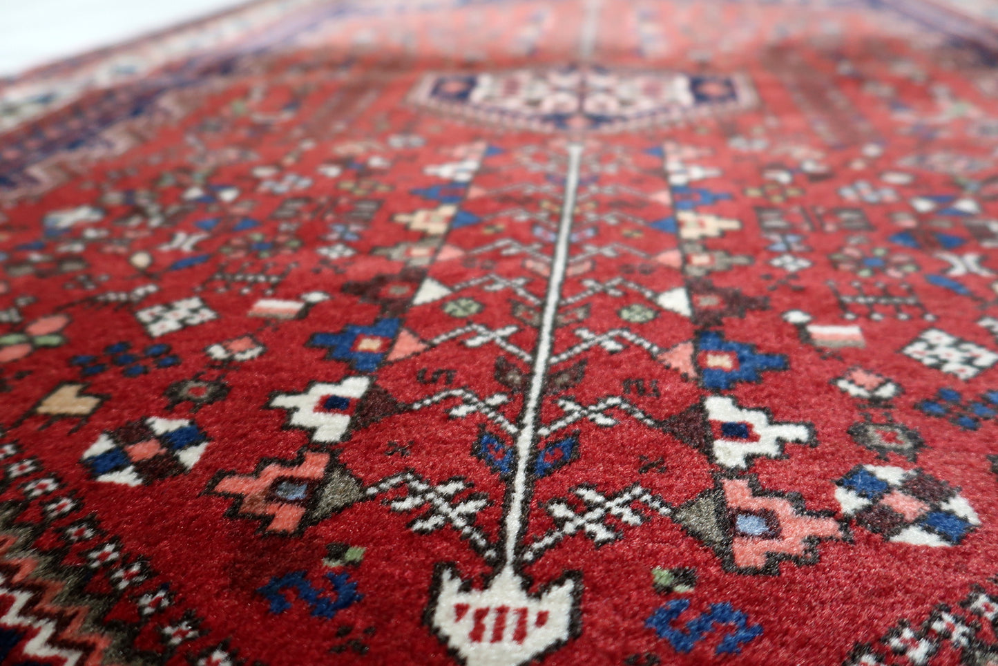 Corner detail showing intricate layering of patterns on antique Persian Qashqai village rug
