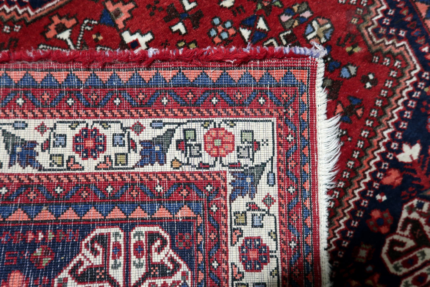 Deep red wool pile of antique Persian Qashqai rug from the 1920s with navy blue accents
