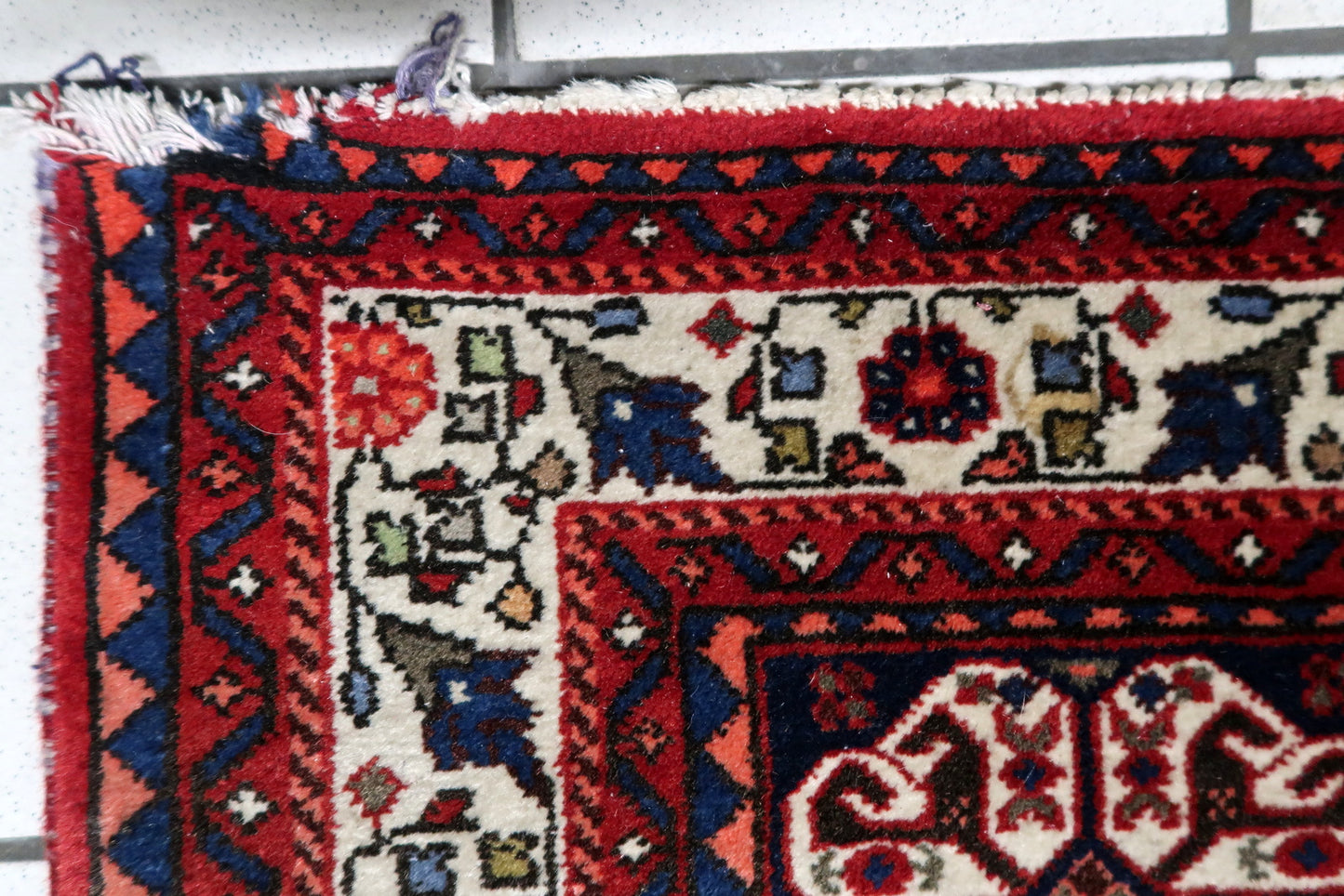 Texture detail of hand-spun wool on a 100-year-old Persian tribal carpet
