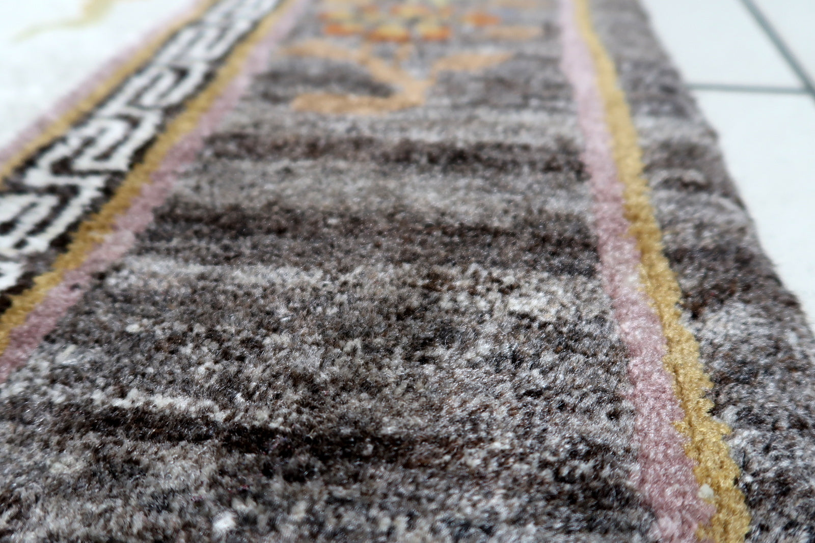 Corner detail showing variegated charcoal-brown field with natural color abrash variations
