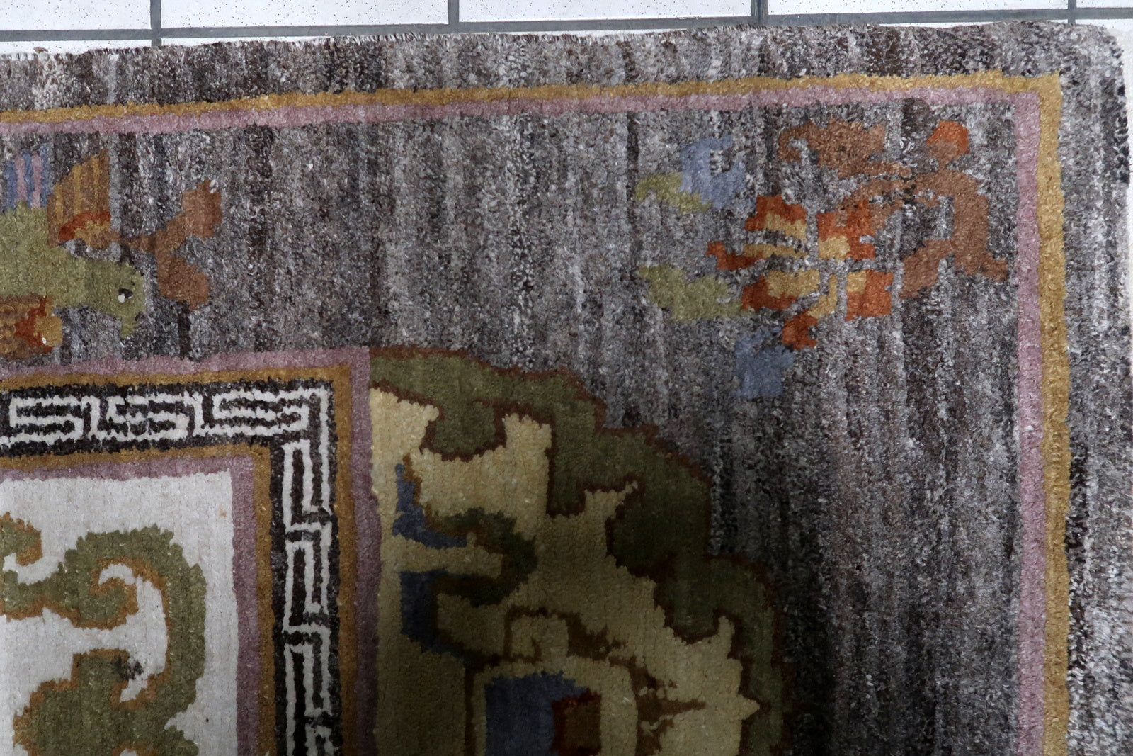 Mid-century Tibetan sitting rug with charcoal brown field and golden-yellow pagoda medallions on floor

