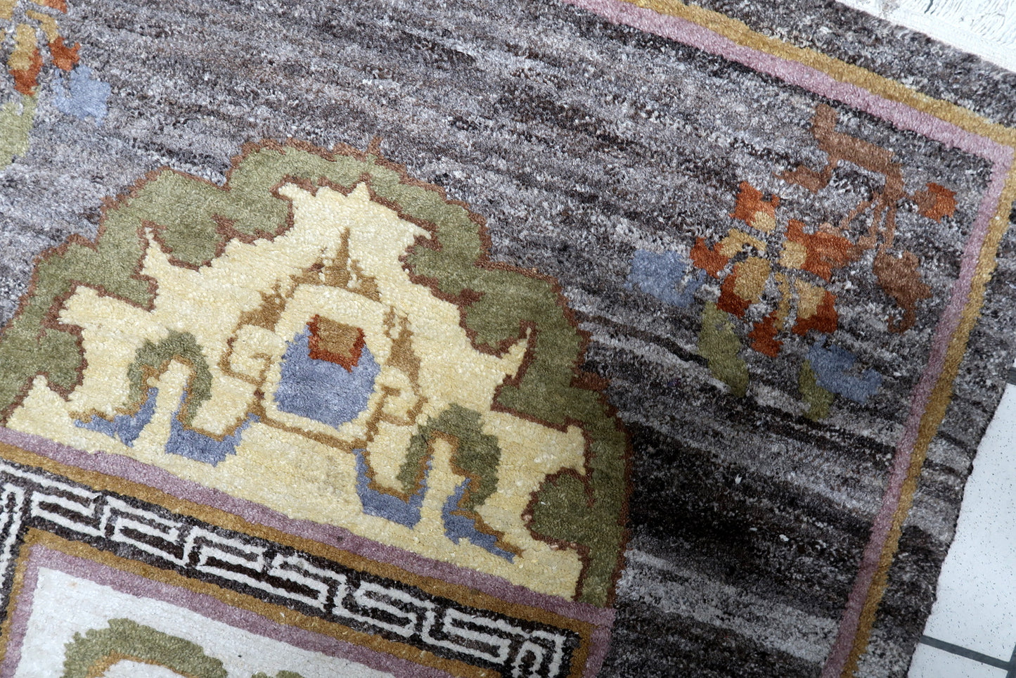 Close-up of vintage Tibetan Khaden rug displaying triple-medallion composition and Greek key border

