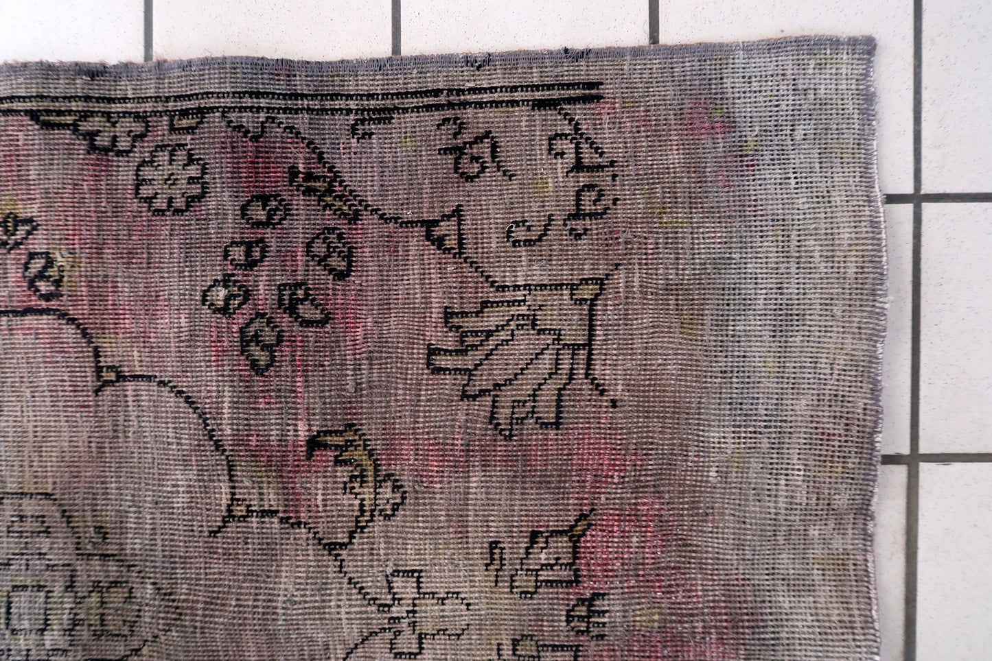 Mid-century distressed Anatolian rug from central Turkey with sun-faded terracotta and weathered charcoal palette on floor

