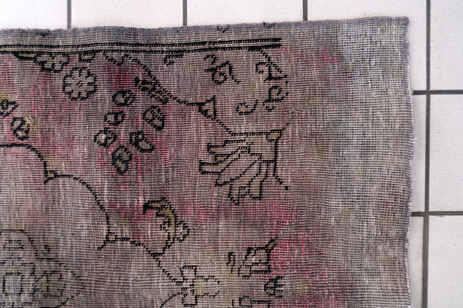 Mid-century distressed Anatolian rug from central Turkey with sun-faded terracotta and weathered charcoal palette on floor

