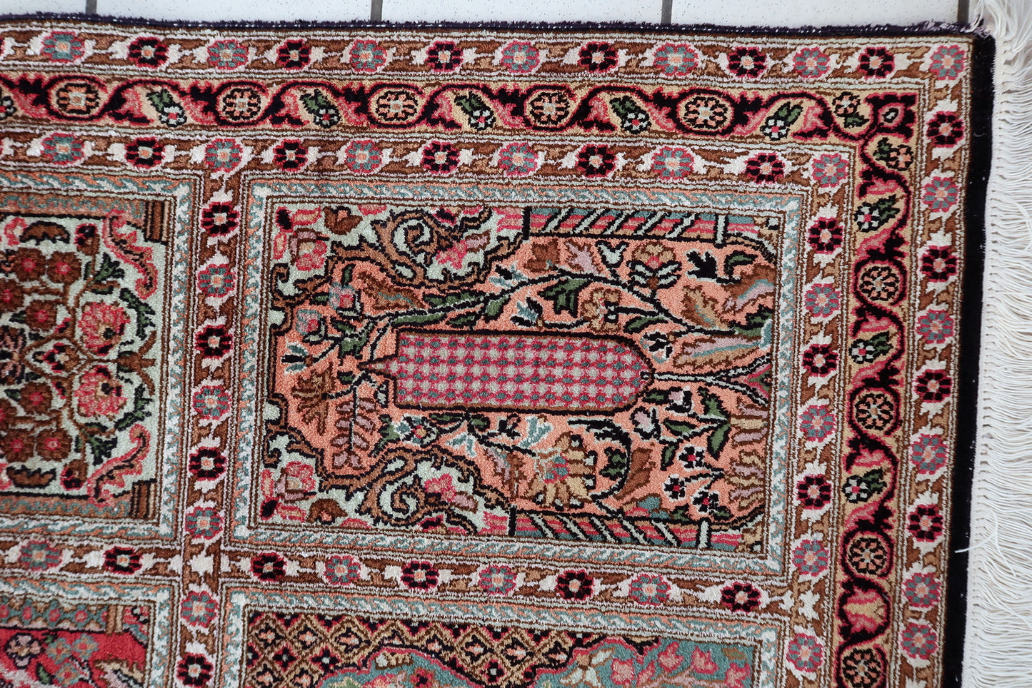 Qum silk rug corner detail, showcasing intricate border and aged patina