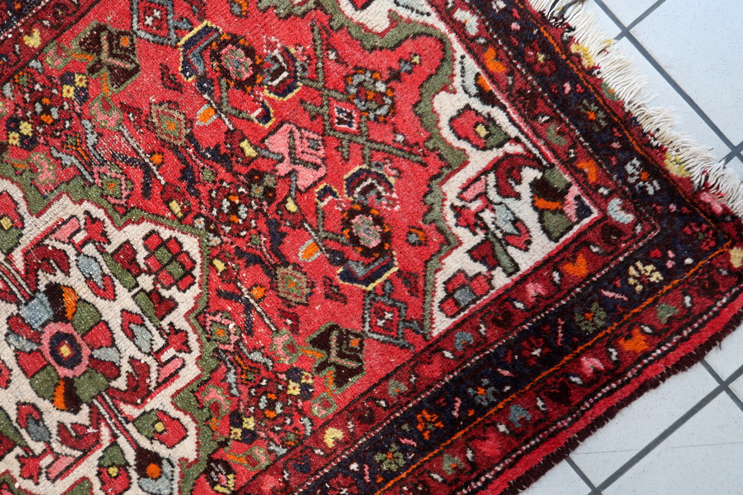 Full composition of an antique Persian Hamadan carpet circa 1920s, featuring a symmetrical floral medallion and tribal-inspired botanical motifs.


