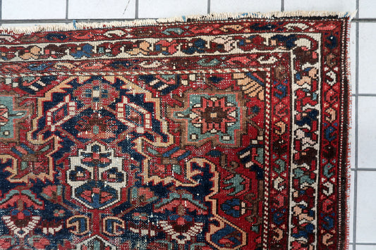 Close-up view of an authentic 1920s Persian Hamadan rug showing beautiful aged patina, low pile central field, and striking central medallion surrounded by tribal motifs.

