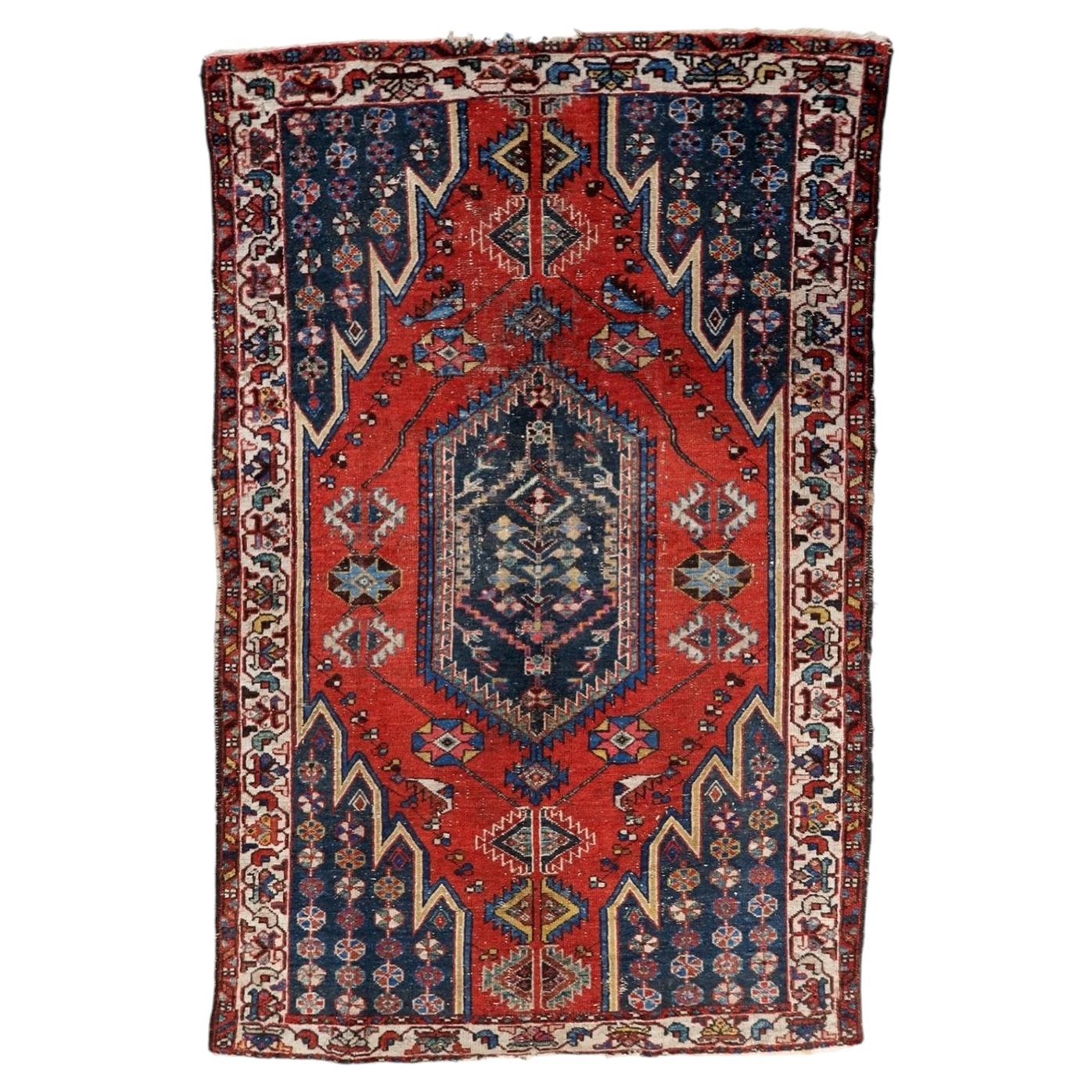 Handmade antique Persian Hamadan rug from the 1920s with a distressed finish, featuring a vivid red field and a central geometric medallion on a 4.2 by 6.4 foot wool carpet.


