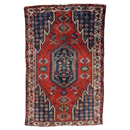 Handmade antique Persian Hamadan rug from the 1920s with a distressed finish, featuring a vivid red field and a central geometric medallion on a 4.2 by 6.4 foot wool carpet.

