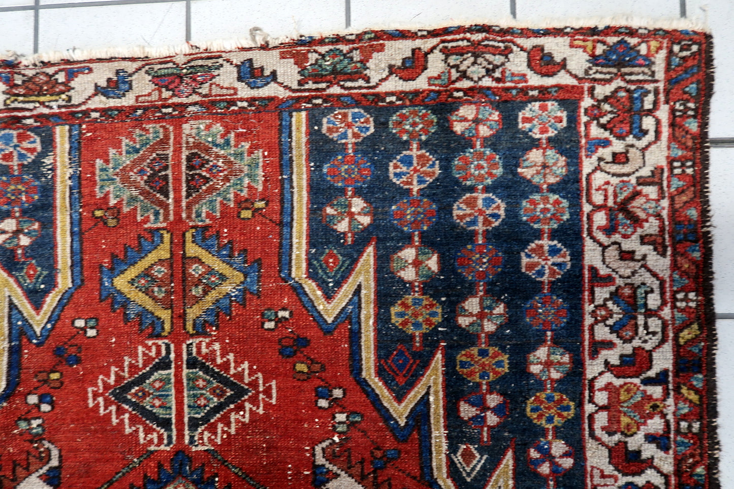 Vintage 1920s Persian Hamadan rug in red and navy blue, showcasing a tribal geometric design, intricate ivory border, and worn, low-pile texture suitable for eclectic interiors.

