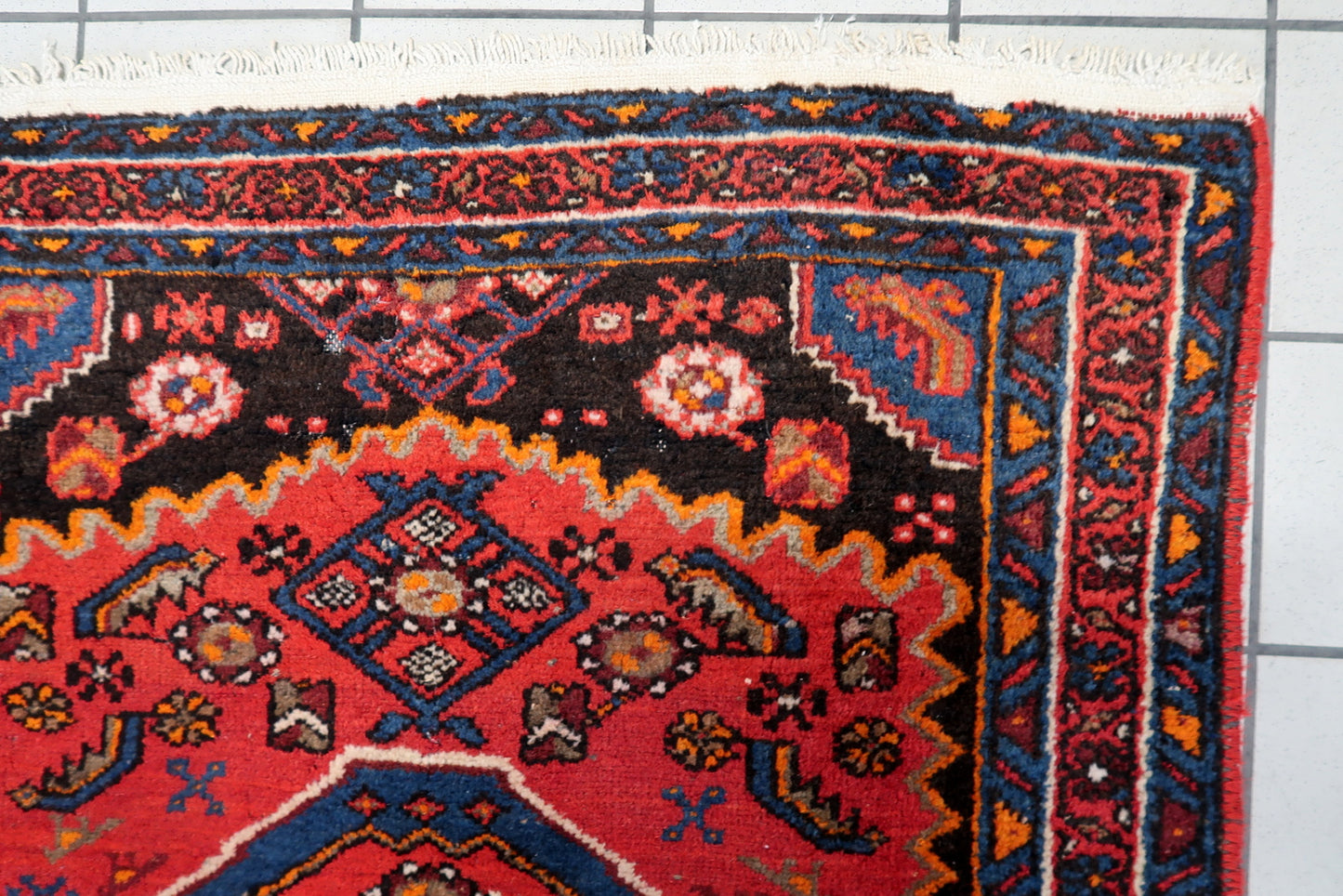Vintage 1930s Persian Hamadan rug with strong, saturated colors, showcasing a bold tribal design with accents of orange, soft blue, and earthy tones on a rich red background.


