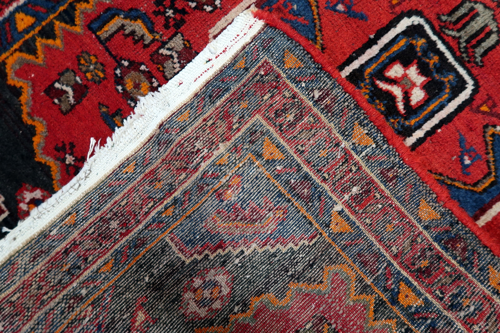 Vintage wool rug with bright, saturated colors and a stylized central medallion, perfect for adding a pop of traditional Persian design to a compact space.

